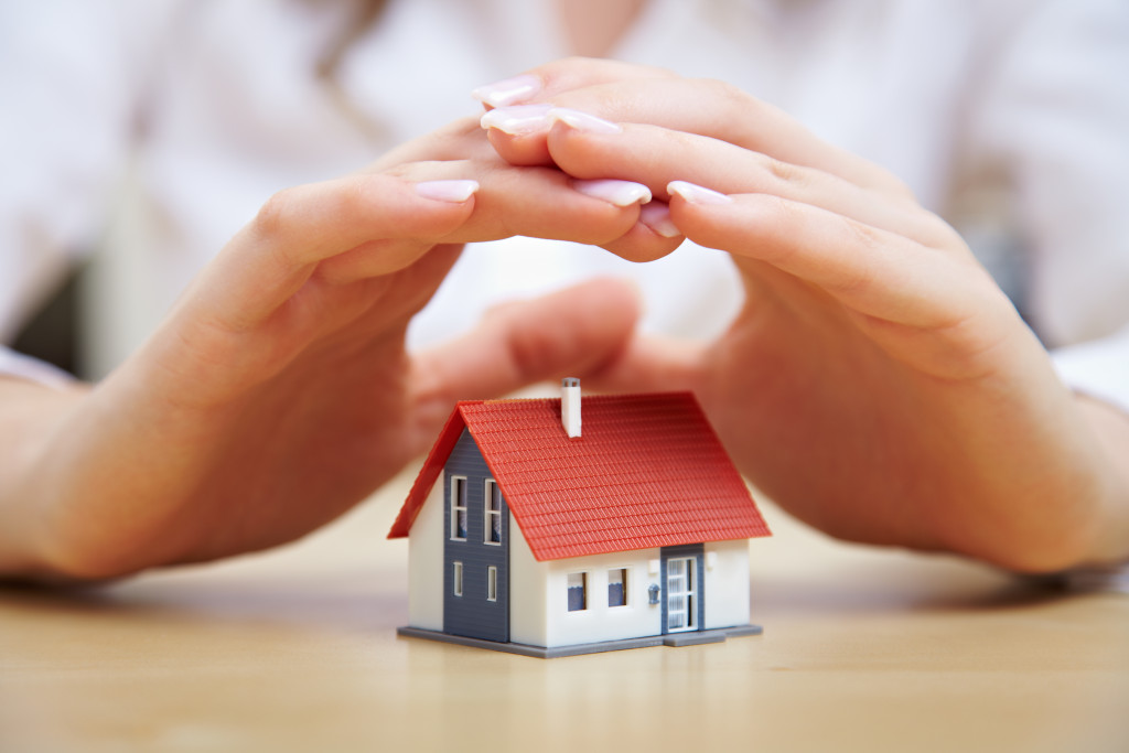 hands hovering over miniature house model