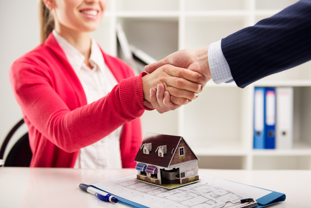A new homeowner shakes hands with her real estate agent