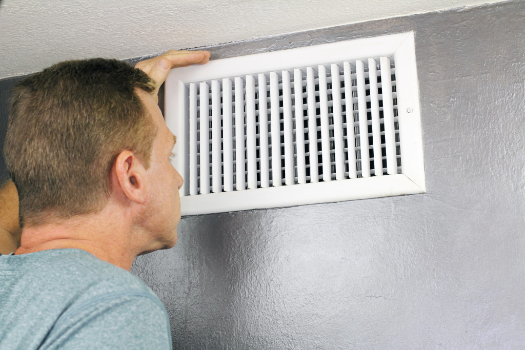 man examining air vent and duct if cleaning is needed