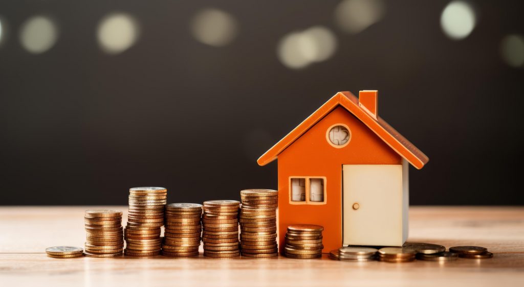 red miniature house and stacked coins
